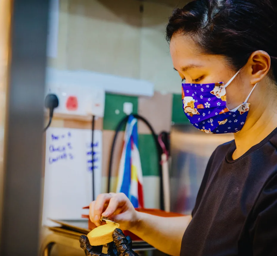 A baker finishing a small pastry by hand inside the cat in the hat stall at Golden Mile Food Centre